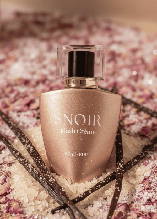 Snoir Blush Creme perfume bottle on a decorative background with vanilla beans and flowers.