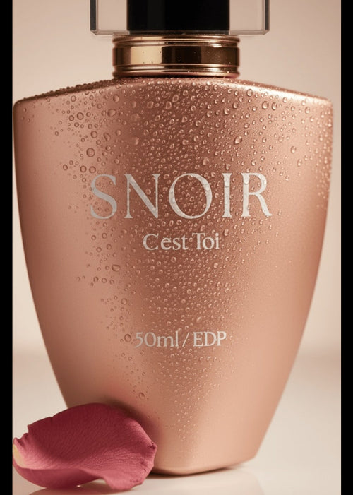 Perfume bottle labeled 'Snoir Cest Toi' with a pink rose petal on a beige background